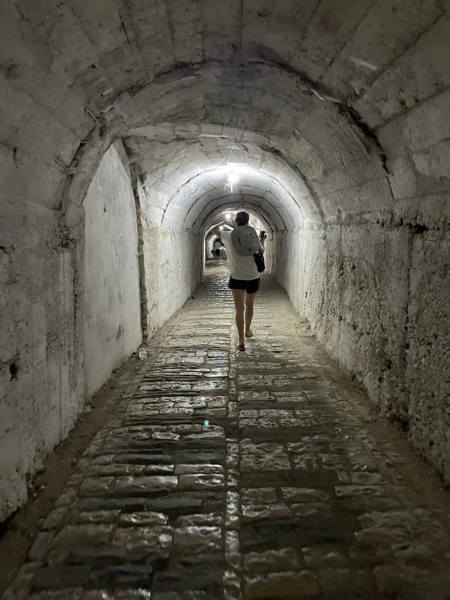 person walking through a dimly lit stone tunnel in Albania