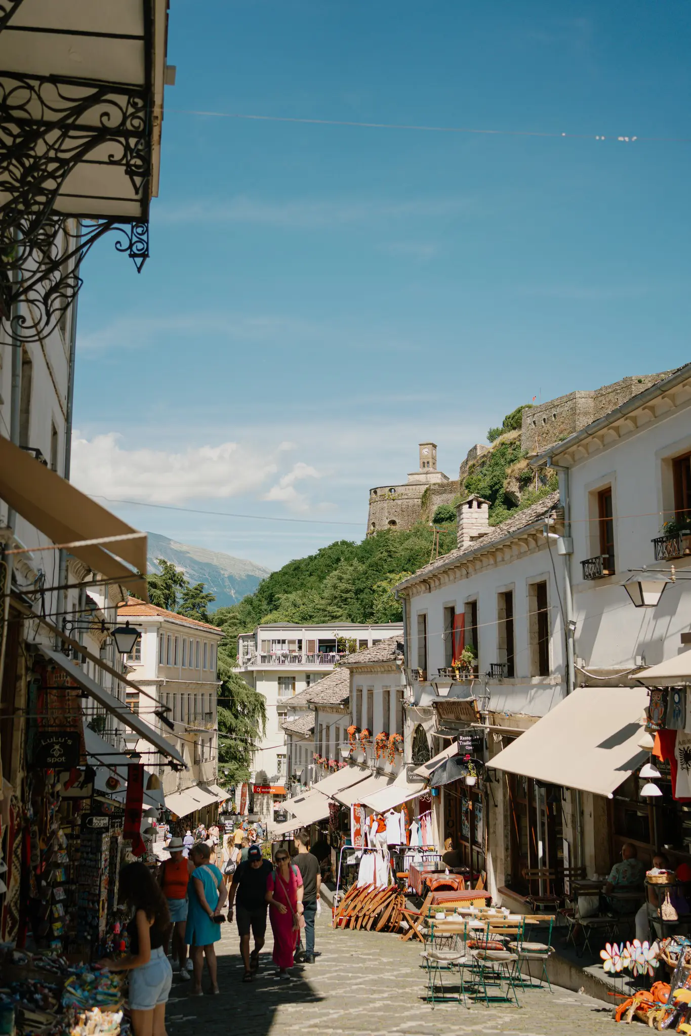 cobblestone street with shops and people in Gjirokaster, Albania